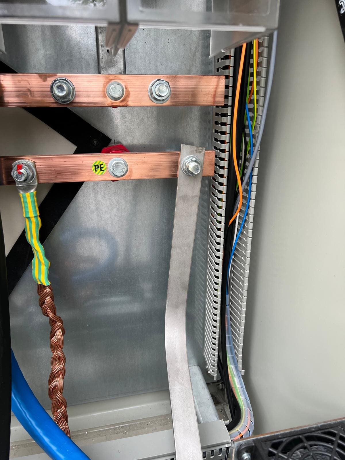 PE bar with earthing strip and braided copper conductor next to a wiring duct with control cables